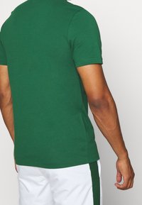 Grön bomulls pikétröja med korta ärmar och en figurnära passform, med enfärgad textur och standardringning.