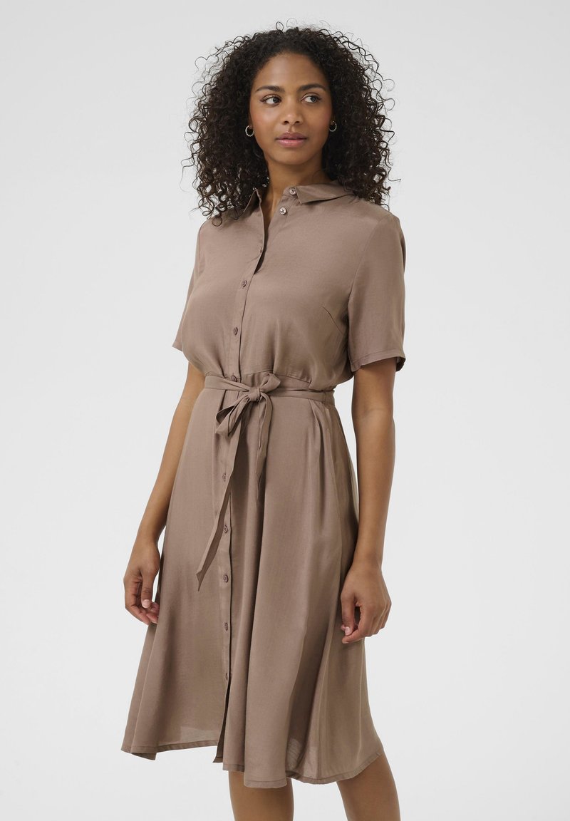 Robe à manches courtes avec boutons en tissu marron doux, cintrée à la taille avec un lien, arrivant au mollet.