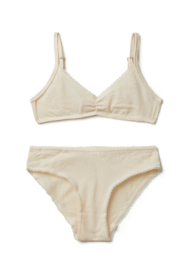 Conjunto de lencería beige que incluye un bralette texturizado con tirantes ajustables y unas braguitas de estilo bikini a juego, ambas con bordes ondulados.