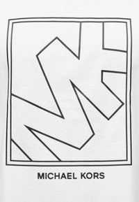 Λευκό βαμβακερό T-shirt με έντονο μαύρο γραφικό σχέδιο από επικαλυπτόμενα γράμματα και σχήματα, με την επιγραφή «MICHAEL KORS» κάτω από το σχέδιο.