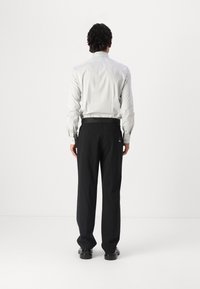 Formele lichtgrijze shirt met lange mouwen, gecombineerd met zwarte getailleerde broek. Glad materiaal met een klassieke snit en achterzakdetail.