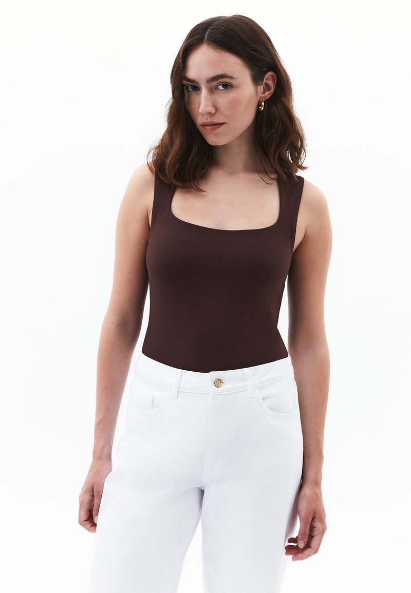 Hnědý top bez rukávů se čtvercovým výstřihem, kombinovaný s bílými džínami s vysokým pasem, hladká tkanina a minimalistický design.
