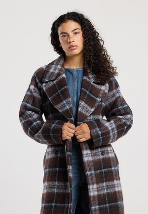 Jas met een bruine en blauwe ruitpatroon, oversized kraag en grote knopen. Gemaakt van een wolachtige stof met een zachte textuur.