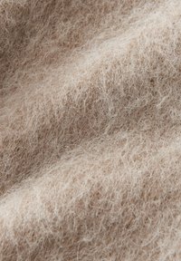 Soft, curly beige wool fabric with fine fibers creating a textured, fuzzy surface.