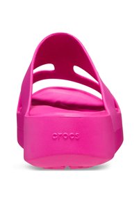 Des Crocs rose vif avec une texture lisse, une sangle arrière et un design découpé. Présente le logo "crocs" sur le côté.