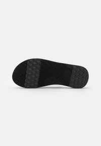 Black rubber shoe sole with a textured pattern featuring star shapes in a grid, smooth center, and rounded toe design.