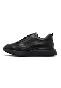 Sneakers in pelle nera con una tomaia testurizzata, punta rotonda e suola in gomma spessa. Presentano lacci e una linguetta sul retro.