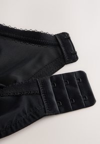 Sezione di reggiseno in mesh nero con bordo smerlato e chiusura regolabile con gancetti a tre file. Texture liscia.