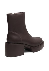 Dark brown leather ankle boot with a chunky square heel, featuring smooth texture and minimal stitching detail.
