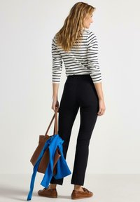 Páskovaný top s dlouhým rukávem v bílé a námořnické barvě, přiléhavé černé kalhoty, hnědá taška a modrý šál. Neformální outfit s volným siluetou.