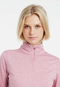 Maglione rosa con zip e colletto alto, realizzato in tessuto testurizzato. Le caratteristiche distintive includono una zip frontale e un logo del brand discreto sul petto.