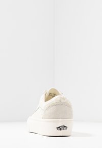 Sneaker Vans w kolorze off-white z zamszowym piętą i wzorzystym materiałem, przedstawiający widok z tyłu z logo "Vans Off The Wall" na podeszwie.