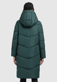Cămașă cu glugă, lungă, �în verde închis, cu un model în formă de v cu o textură netedă, buzunare laterale cu fermoar și o etichetă logo pe tiv.
