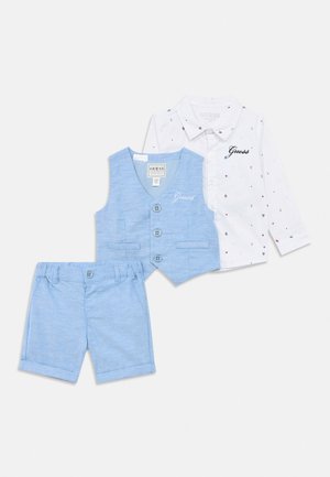 Pantaloni scurți pentru copii de culoare albastru deschis, vestă asortată cu nasturi și cămașă albă cu mânecă lungă, având imprimeuri nautice mici și logo-ul "Guess".