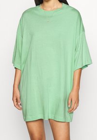 Camiseta de gran tamaño en verde menta, fabricada en algodón suave, con cuello redondo y mangas cortas, con una textura lisa y sencilla.