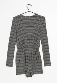 Svartvit randig långärmad romper, med elastiskt midjeband och shorts, tillverkad av ett mjukt tyg med en slät textur.