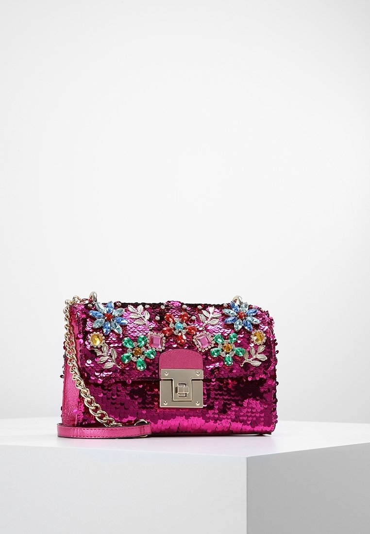 Vaaleanpunainen paljettikäsilaukku, jossa kukkakoristeita ja jalokivikoristeita. Varustettu hopeisella ketjuhihnalla ja etuklammen sulkemisella. Suorakulmainen muoto.