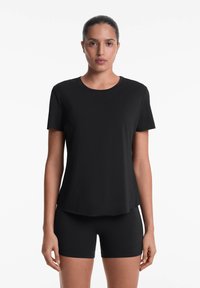 Black short-sleeve T-shirt featuring a round neckline and a relaxed fit, paired with matching black shorts, made from a smooth, stretchy fabric.