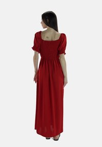 Lang rød kjole med smocked bodice og puffede ærmer, der har en firkantet ryg og en flydende nederdel, lavet af letvægtsstof.