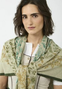 Écharpe tricotée avec des motifs floraux en sarcelle, vert et or sur un fond beige. Texture douce avec une bordure verte.