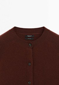 Tmavě burgundský kašmír svetr s kulatým výstřihem, který má pět knoflíkových zapínání a pružné manžety a lem. Měkká, texturovaná tkanina.