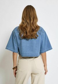 Gekürzte Jeansjacke in Hellblau mit kurzen Ärmeln, ausgestattet mit einer Rückenpasse und einer lockeren Passform. Material: Jeans. Schlichte Gestaltung ohne Muster.