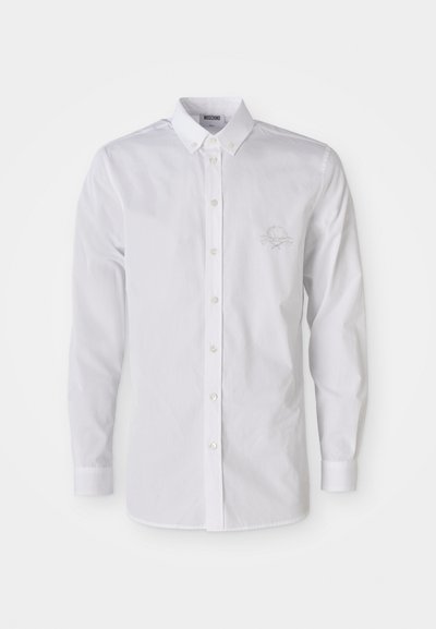 Balta ilgomis rankovėmis marškiniai su mygtukų užsegimu, mygtukų įsisegimui ir subtiliu siuvinėjimu kairėje krūtinės pusėje.