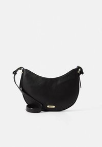 Black leather crossbody bag with a curved shape, gold hardware accents, and a thin adjustable strap. Features a logo plate on the front.