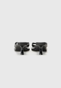 Sandales noires à talons avec une finition lisse et brillante, un design ouvert à l'avant et un talon étroit et effilé. Des sangles texturées se croisent sur le pied.