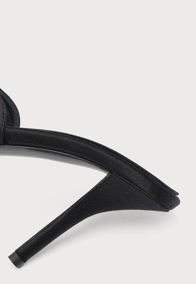 Sandale noire à talon haut avec un talon aiguille fin et un design à bout ouvert, présentée sur un fond clair uni.