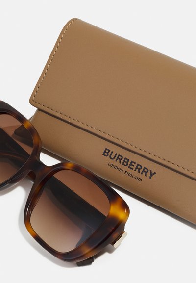 Žirafos akinių rėmeliai su rudu gradientiniu lęšiu, kuriuos lydi šviesiai ruda odinė dėžutė su išpjautu "Burberry" prekės ženklu.
