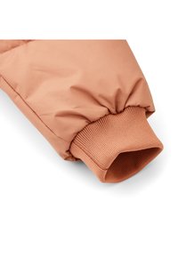 Light orange padded coat sleeve featuring a textured knit cuff. The fabric is smooth with a matte finish and subtle sheen.