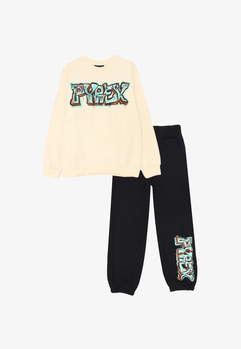 Felpa crema con grafica colorata "PYREX" sul davanti, abbinata a pantaloni della tuta neri con lo stesso logo sulla gamba. Tessuto in misto cotone.