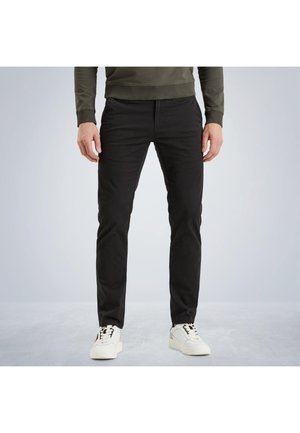 Schwarze, enganliegende Hosen aus Stretch-Baumwolle, mit Reißverschluss, Gürtelschlaufen und seitlichen Taschen. Tragen sie mit weißen Sneakern.