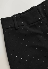 Black trousers with an elastic waistband, featuring a textured fabric and small, silver polka dot pattern throughout.