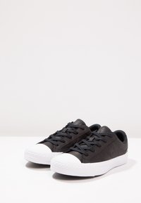 Sneaker in pelle nera con punta in gomma bianca, design con lacci, dettagli testurizzati e suola a motivo.
