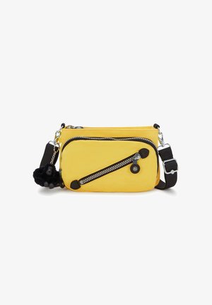 Žlutá crossbody taška s dvěma zipovými kapsami, černými koženými akcenty a chlupatým přívěskem. Má nastavitelné ramenní popruhy a texturovanou látku.