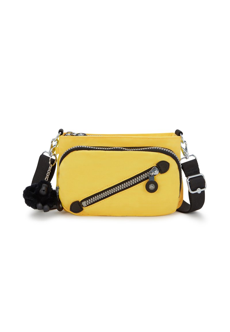 Keltainen olkalaukku, jossa on kaksi vetoketjullista taskua, mustat nahka-akuutit ja karvainen koriste. Ominaisuudet ovat säädettävä hihna ja teksturoitu kangas.
