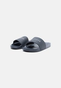 Black slide sandals made of synthetic material, featuring a wide strap with white logo text and a textured footbed for grip.