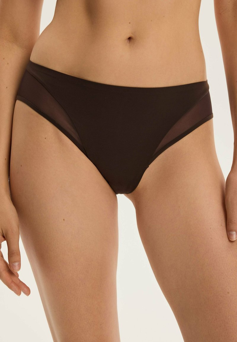 Schwarze Bikini-Unterhose mit transparenten Netzseitelementen, die einen tief sitzenden Schnitt bieten. Glatter Stoff mit einem leichten Glanz und minimalistischem Design.
