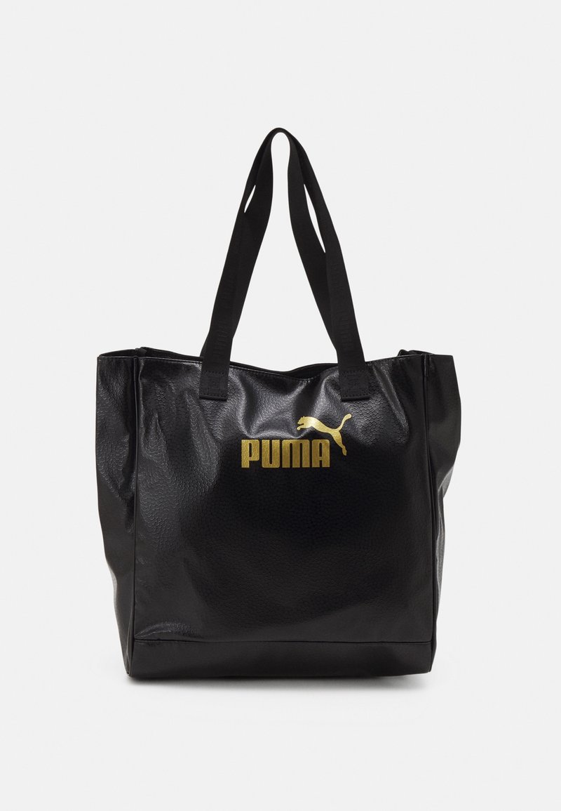 Sac fourre-tout noir texturé avec deux poignées, arborant un logo Puma doré et un emblème de chat sautant au centre à l'avant.