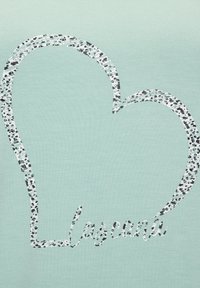 Svijetlo mentol zelena majica s dizajnom srca napravljenim od crnih i bijelih točkica, s riječju "lasagna" u razigranom fontu ispod.