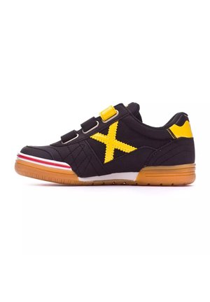 Zapato deportivo negro con un acento amarillo, que presenta un gran logo amarillo en forma de 'X', tres tiras de Velcro y una suela de goma con rayas rojas.