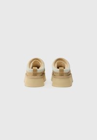 Tan suede shoes with a textured, multicolored woven trim around the collar, cushioned interior, and a thick, durable rubber sole.