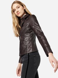 Bruine leren jas met een ritssluiting aan de voorkant, staande kraag en twee zijzakken. Gestyled met een aansluitende grijze spijkerbroek met een fluwelen streep.