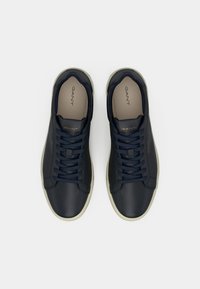 Adidași din piele bleumarin cu un finisaj neted, vârf rotund, talpă din cauciuc alb contrastant și șireturi bleumarin închis. Branding pe limbă și pe lateral.