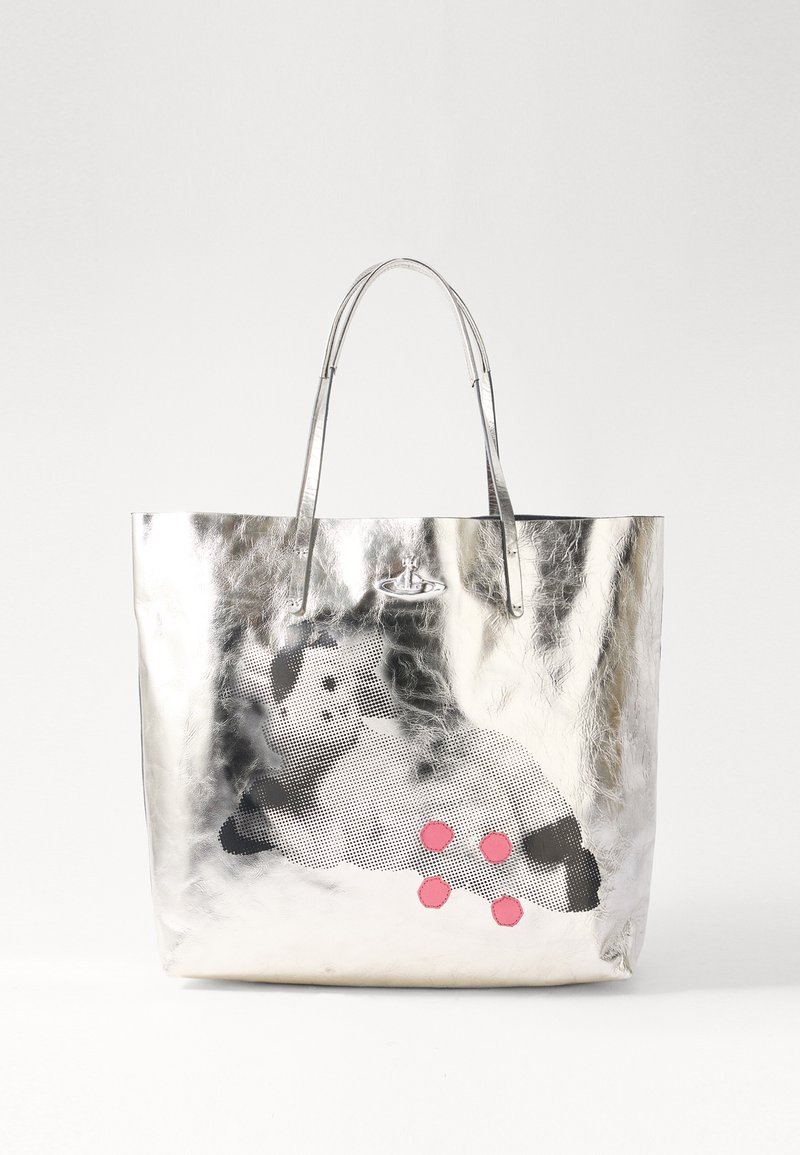 Silverfärgad metallisk tote bag med två handtag, prydd med ett svartvitt prickigt mönster och tre rosa detaljer på framsidan.