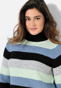 Gestreifter Pullover mit einem Rollkragen-Design. Die Farben umfassen Schwarz, hellgrün, Grau und Blau. Hergestellt aus einem strukturierten Strickmaterial.