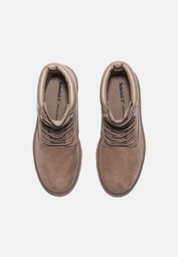 Braune Wildleder-Stiefeletten mit strukturiertem Obermaterial, runden Schnürsenkeln und gepolsterter Kante. Geriffeltes Gummiband für guten Halt. Timberland-Logo im Inneren.
