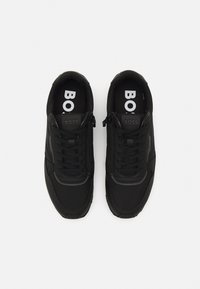 Paire de baskets noires BOSS avec lacets et fermetures éclair latérales, vue de dessus sur fond blanc.